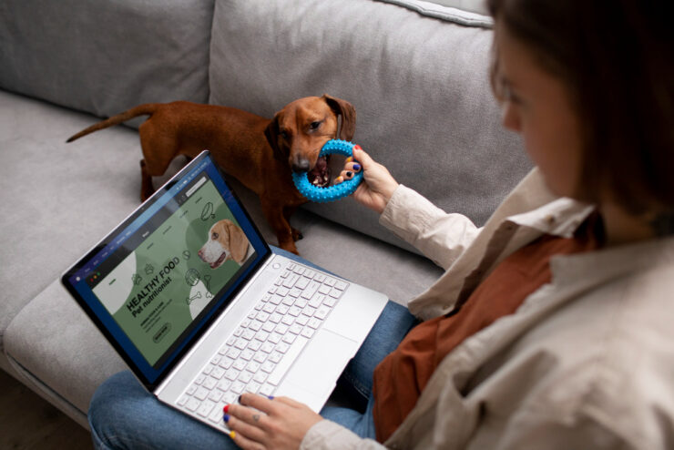 Mulher mexendo no computador e brincando com o cachorro