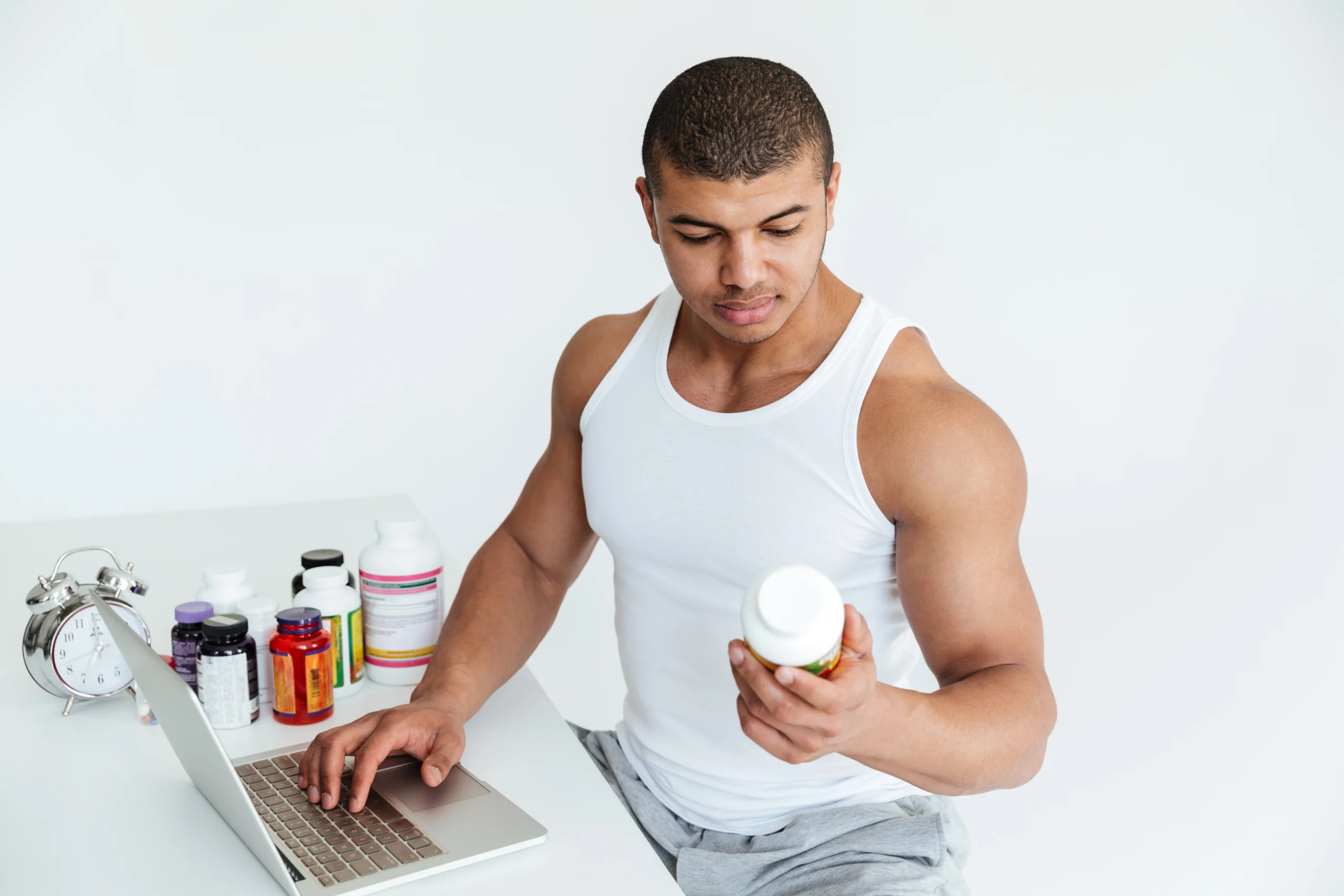 desportista-jovem-bonito-segurando-nutricao-esporte-e-usando-o-computador-portatil